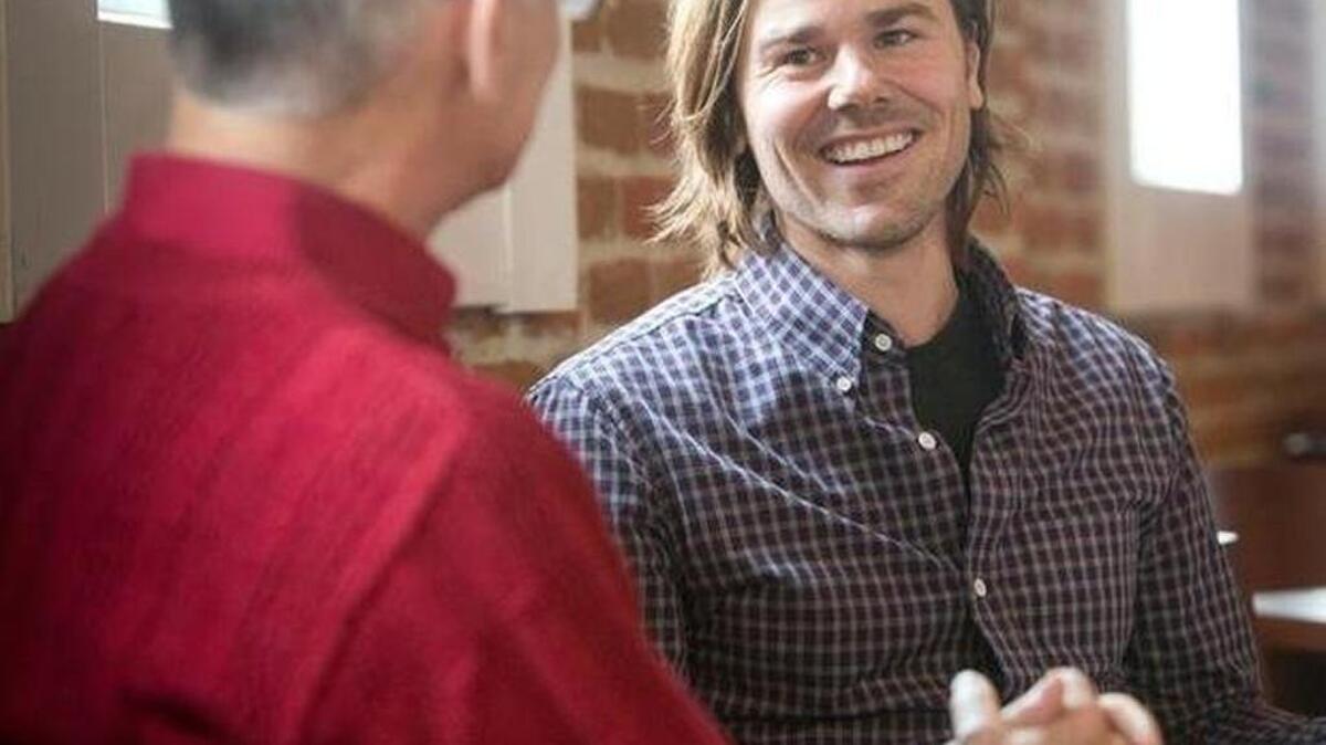 Dan Price, right, laughs as he talks with his father, Ron Price, during an interview with the Statesman last December.