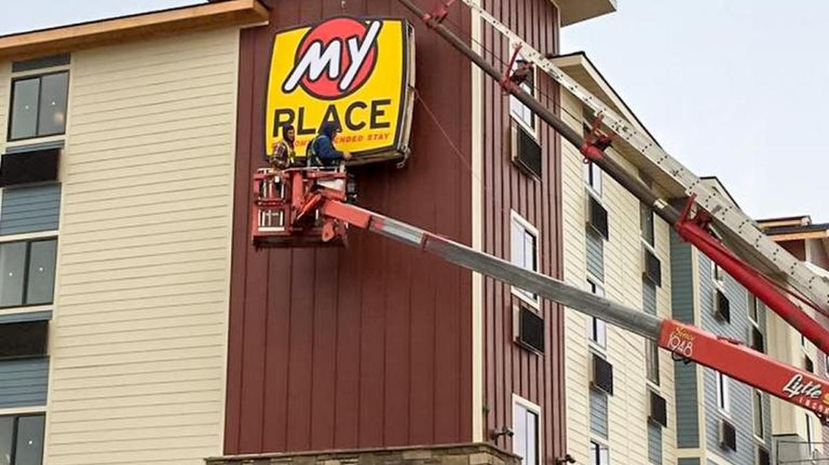 Workers place a sign on the side of the hotel.