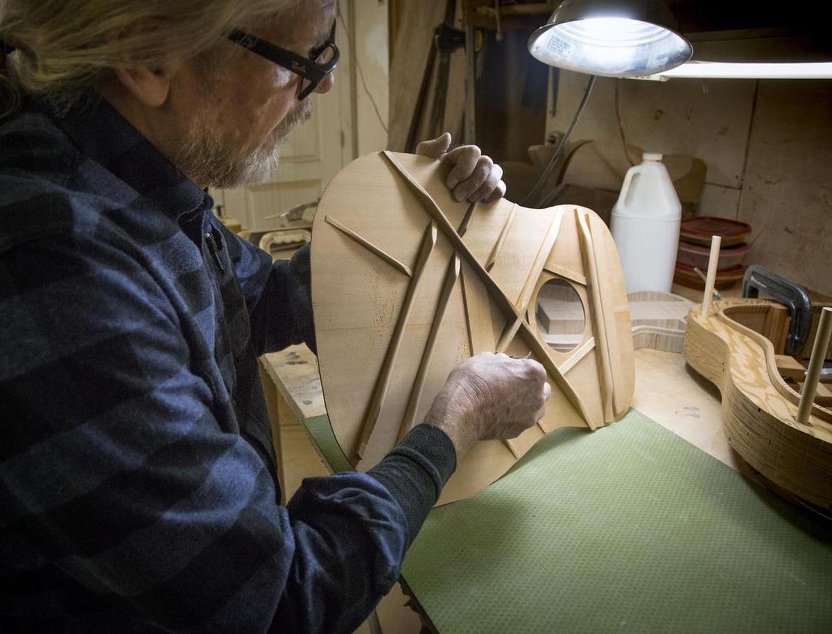 John Bolin shapes the tone bars fitted to an acoustic guitar.