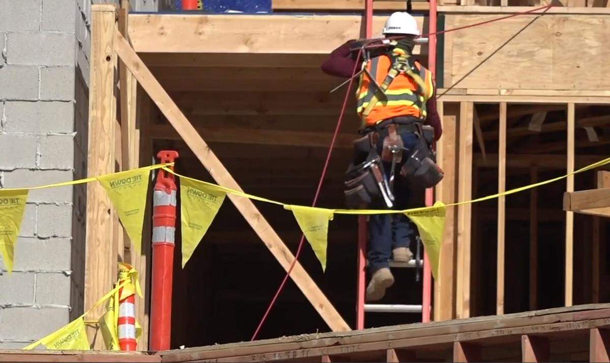 A worker climbs a ladder at the Park Place Apartments. Okland is building the apartments for Gardner Co., the developer.