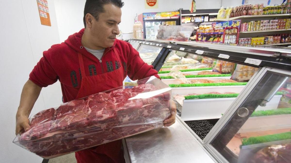 Charlie Aguirre has 33 years experience as a butcher. Brisk business keeps him busy refilling the meat case.