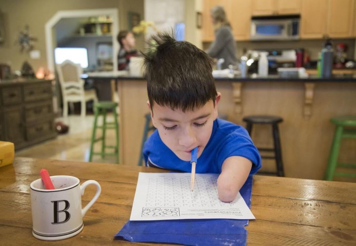 While his mother makes dinner and his brothers work on their homework, Bowen Toomey does his homework. He writes by holding a pen or pencil in his mouth.