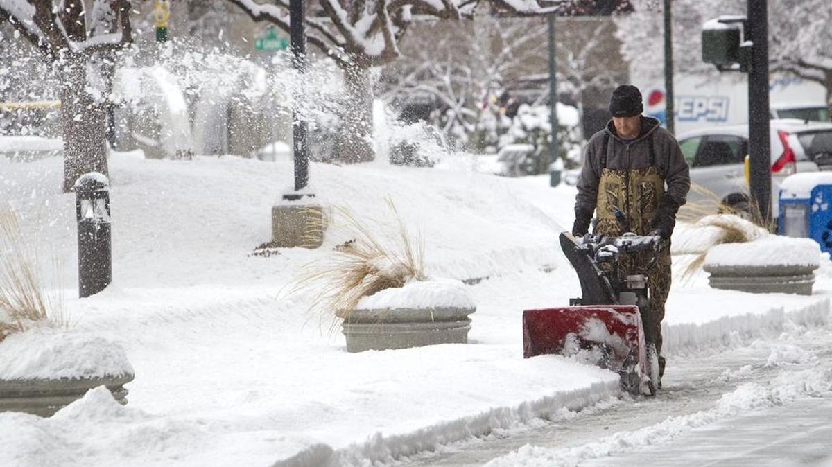 Zach Parks, with Pro Care Landscape Services, clears overnight snow from around the Wells Fargo Center Wednesday morning. "Busiest winter in 30 years," says company president Rodger Erstad.