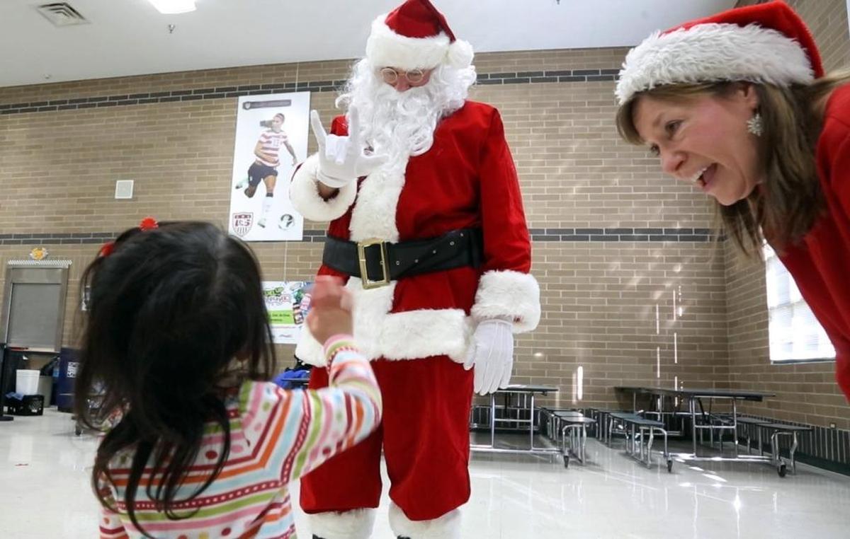 Leilani Wong, 2, waves goodbye to Santa, who signs “I love you” in return. For more than two decades, Sonny Cabbage has been Santa for deaf and hard-of-hearing children at Ponderosa Elementary School after he was asked by Jill Muir, right, to fill the role.
