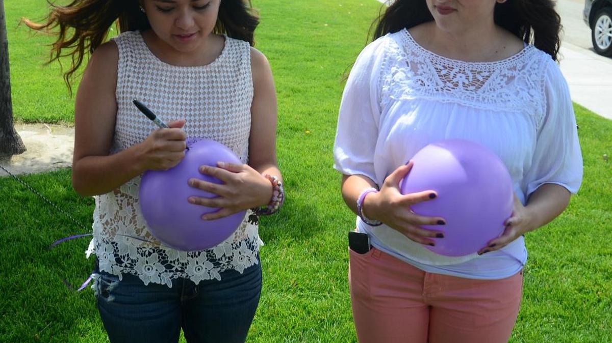 Judy Diaz, left, Godinez's daughter, writes a message to her mother on a balloon.
