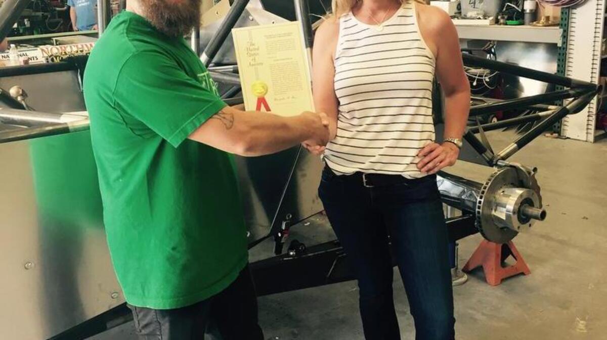 Boise State alumnus and Greenspeed Research founder Dave Schenker receives the technology patent he filed as a student from Katy Ritter, director of the Office of Technology Transfer.