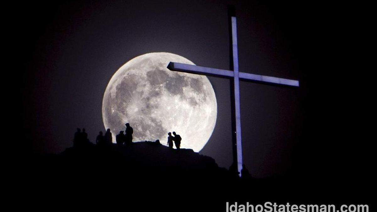 A "supermoon" rises over Table Rock and lighted cross near Boise, Idaho. Saturday June 22, 2013
