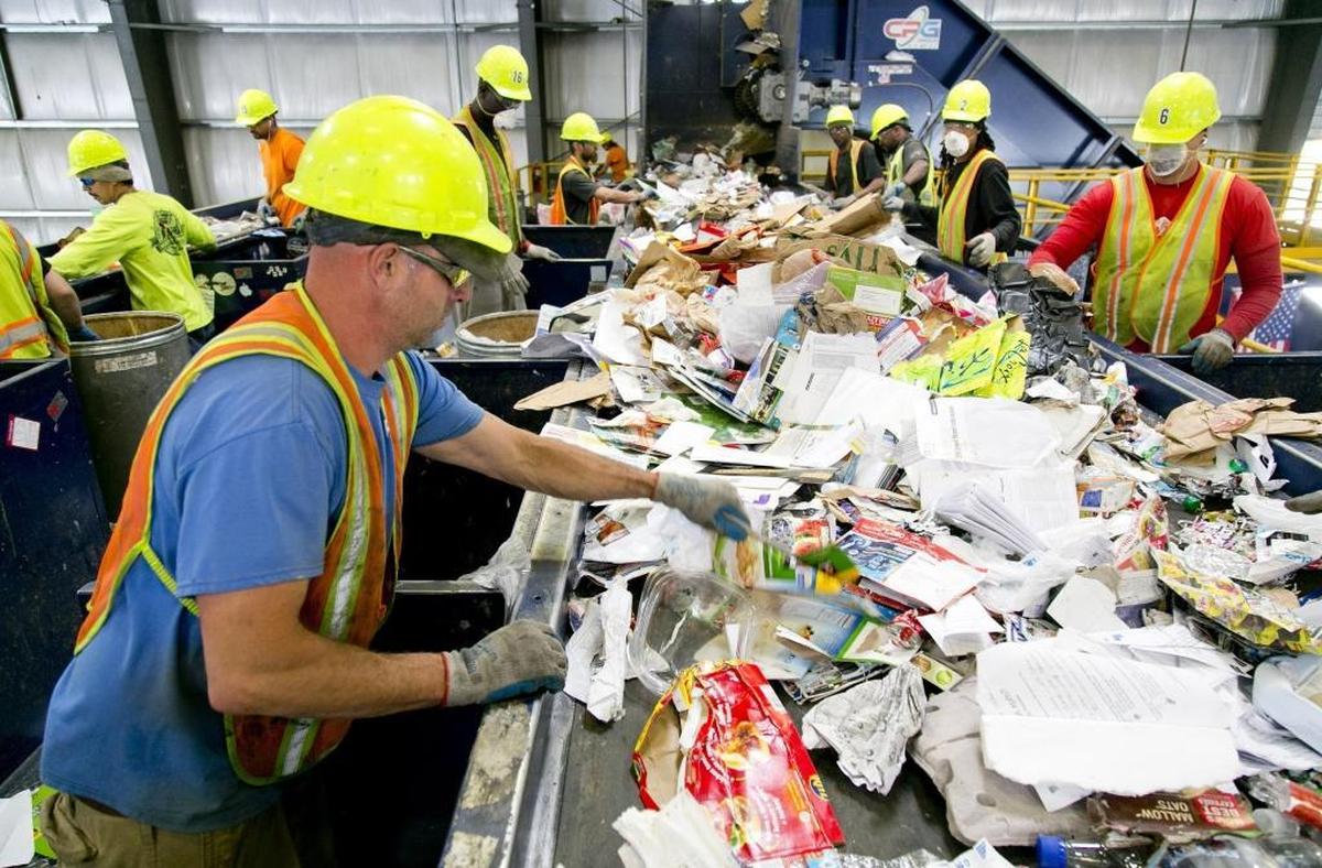 Workers, including Chris Passey (left, foreground) sort through recyclables on the cardboard line at a Western Recycling plant in Boise. A Chinese ban on paper and low-grade plastics has raised the possibility of installing optical sorters at the Boise plant and others like it across the western United States to more effectively clean contaminants out of recycling streams.