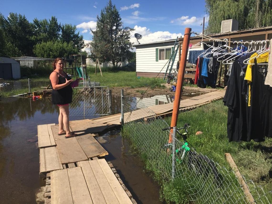 Alisha Cowger stands Friday in front of her home in Riviera Estates Mobile Home Park, where she and her family returned despite a mandatory evacuation order. Wooden pallets have been put down to cross the wet lawn.