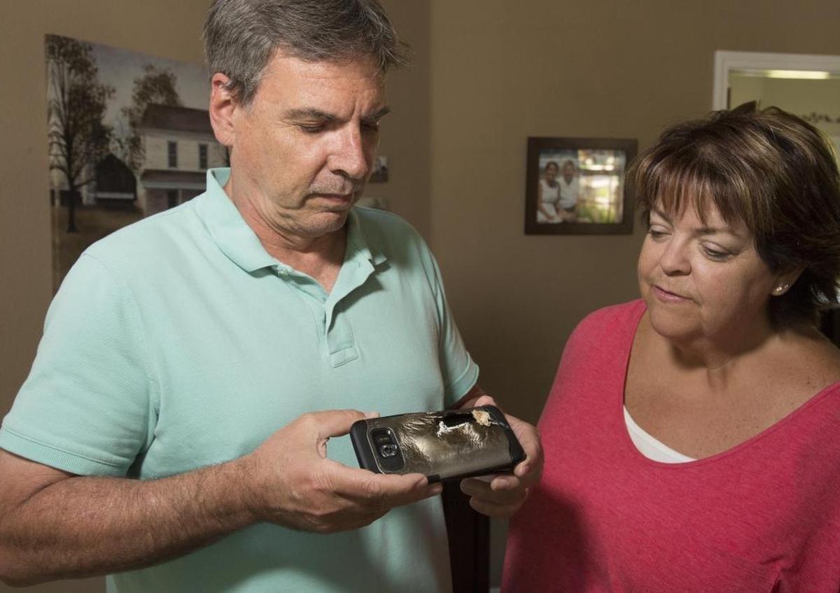 Tony and Theresa Morgan look over the remains of Tony’s Samsung Galaxy S7 Edge, after it exploded while being charged inside a bedroom of the couple’s Eagle home. The explosion destroyed the wireless charger it was attached to and left burn marks on a nightstand. Theresa Morgan quit using her phone, the same model, after the incident.