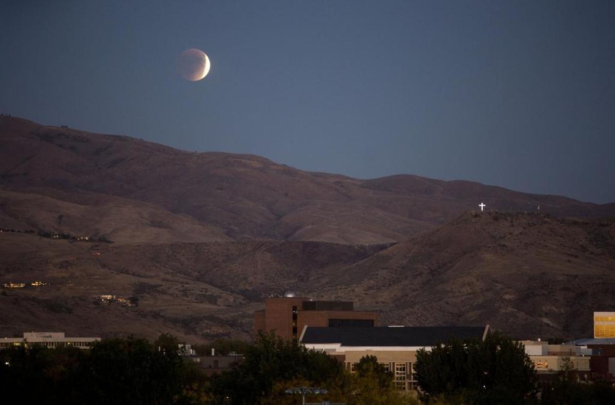 The super moon rises partially eclipsed over the Foothills just after sunset.
