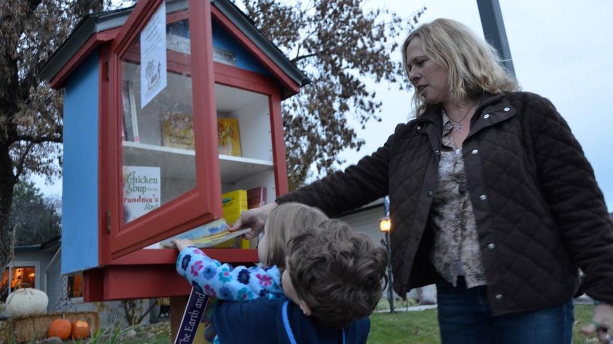 Luke Moore, 6, and his sister Maddie Moore, 3, were the first to make use of the tiny library with help from neighbor Kim Dewit.