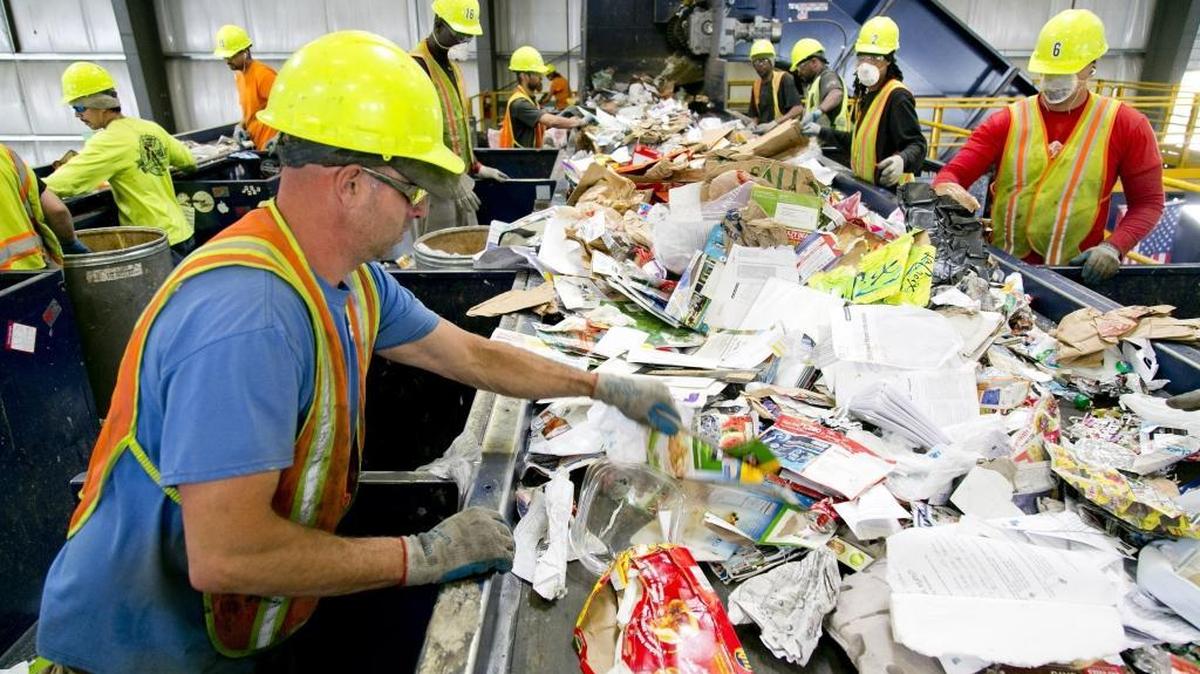 Workers, including Chris Passey (left, foreground) sort through recyclables on the cardboard line at a Western Recycling plant in Boise. A Chinese ban on paper and low-grade plastics has raised the possibility of installing optical sorters at the Boise plant and others like it across the western United States to more effectively clean contaminants out of recycling streams.