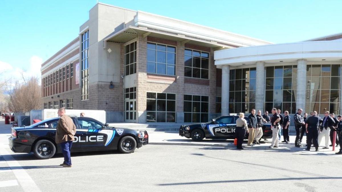 A Boise High School student waits to be driven away Tuesday morning in the police car at left, while officers attend a debriefing after the student came down off the school roof after threatening to kill himself.