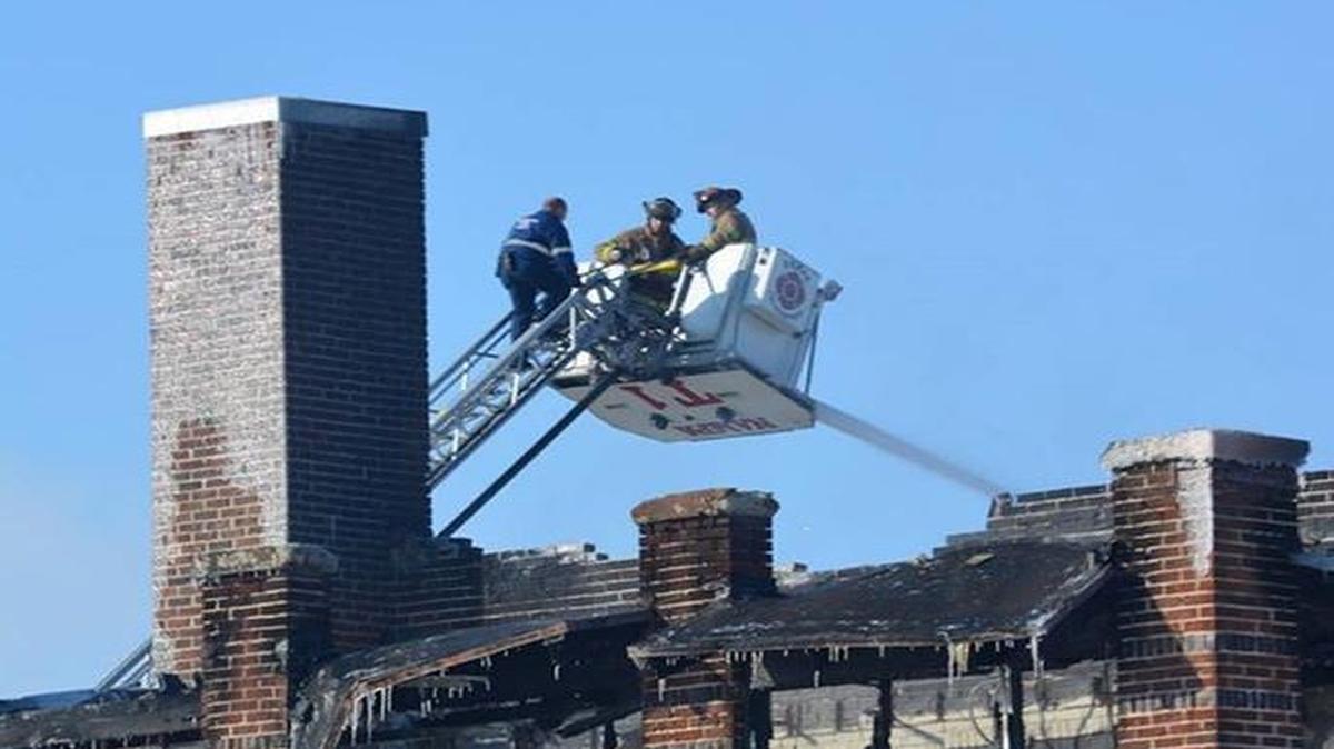 Firefighters on a ladder truck view the damage following the fire at the old Mercy Hospital.