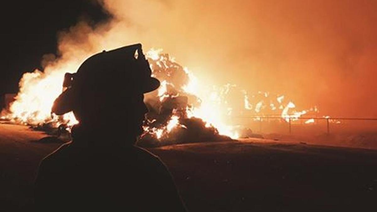 A Kuna firefighter waits for a big haystack fire to become more manageable off Kuna Cave Road early Thursday. No structures were threatened.