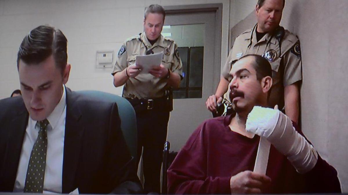 Patrick A. Zavala wraps his injured hand Monday afternoon during a video arraignment transmitted from the Ada County Jail to the Courthouse downtown. Public defender Abraham Wingrove, left, represented Zavala at the hearing.