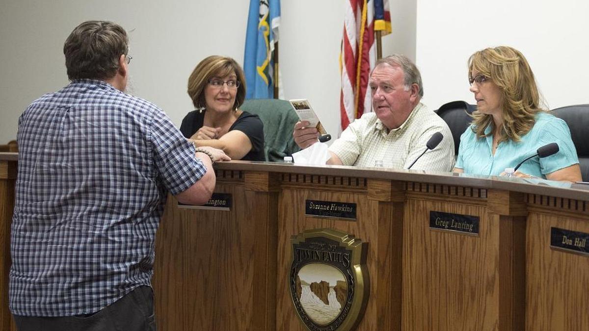 Twin Falls City Councilman Chris Talkington, seated, talks to citizen Terrence Edwards on Monday as Edwards hands copies of the U.S. Constitution to the council. “The Muslim influence is not just a religion — it’s a theocracy,” Edwards said. Councilwoman Nikki Boyd, left, and Vice Mayor Suzanne Hawkins listen.