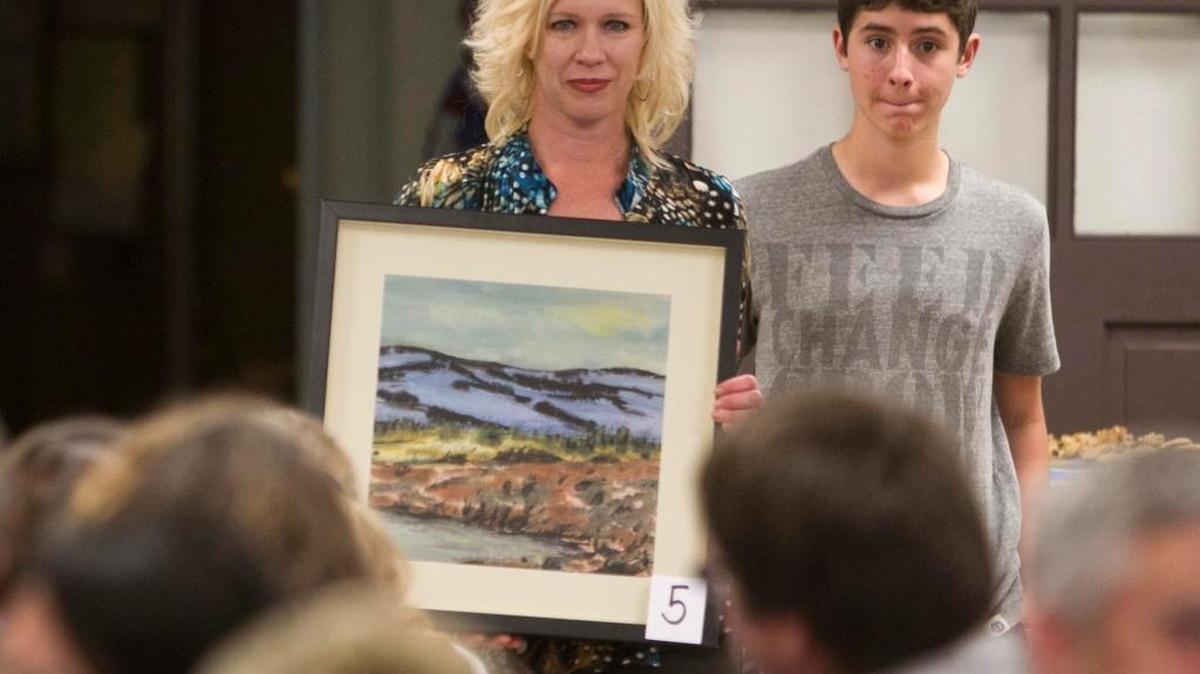 Katy Belanger holds a painting at an auction for the Robert Manwill Scholarship Fund. Belanger, an art teacher from New Plymouth, started the fund one year after Robert’s killing. She has led and expanded it every year since.