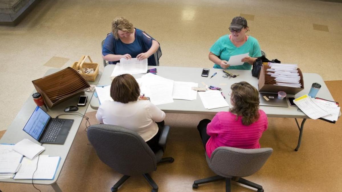 Regina Thomason, facing at left, and Holly Dickinson, facing at right, sign their contracts for the upcoming school year June 14 at Canyon Ridge High School.