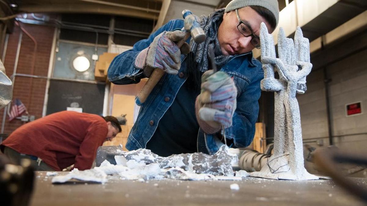 An unidentified student removes the cast from a bronze-and-aluminum pour in Boise State sculpture professor Francis Fox’s art sculpture class.