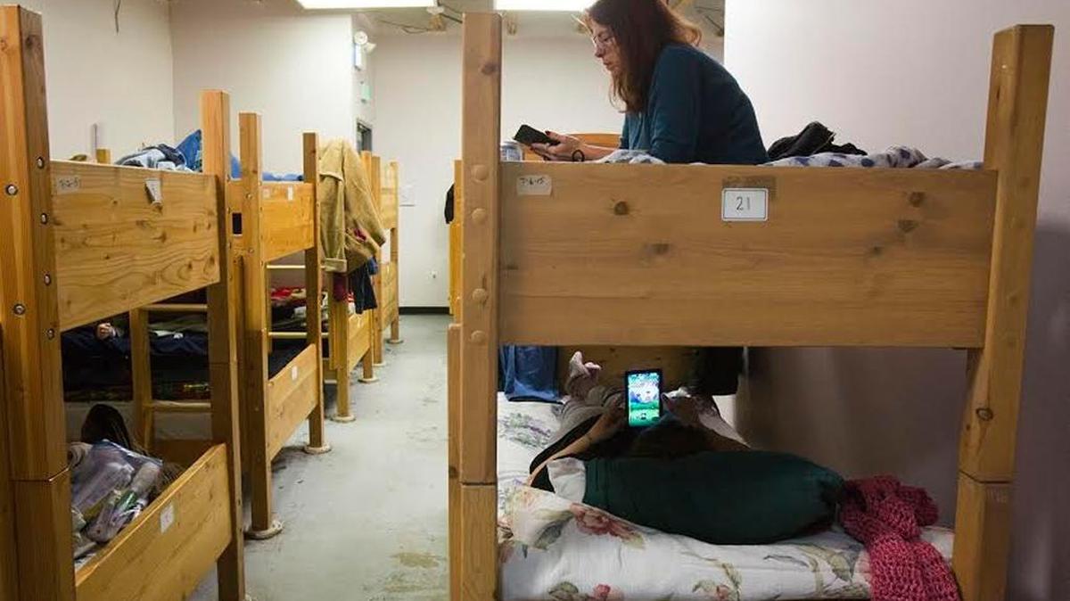 Denise, who has been at Interfaith Sanctuary for three months, reads in her bunk in the women’s dorm. “They treat me like a human being,” she said. She’s starting a new, full-time job soon. Still, it will take a while for her to save enough money to afford a place of her own, she says.