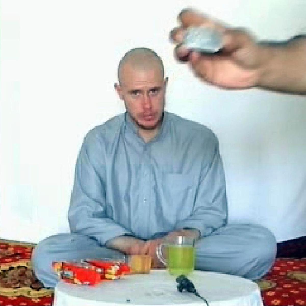 Bowe Bergdahl is shown during his captivity in a still photo taken from a video posted online by the Taliban. One of his captors holds up his Army dog tags to the camera.