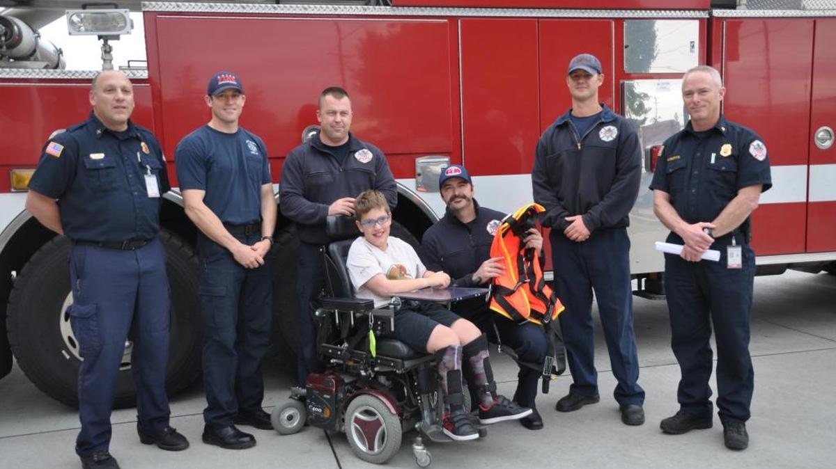JoJo Tuinstra presented a special-needs harness to Boise firefighters on behalf of Courageous Kids Climbing.