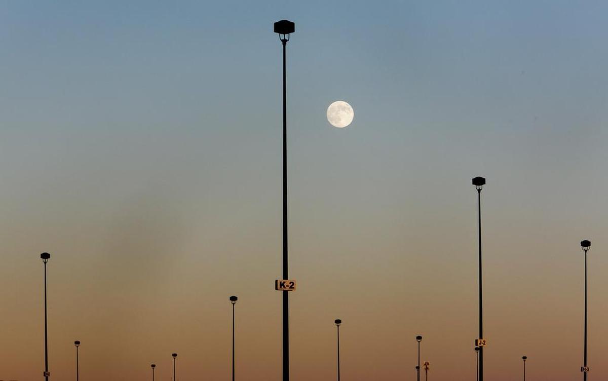 A nearly full moon rises over lights in a parking lot off of Fairpark lane in Boise, Idaho. July's full moon in Boise will be at 12:16pm. Sunday July 21, 2013