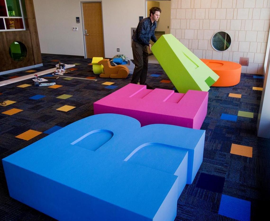 Kevin Winslow, communications manager for the Boise Library, places furniture shaped as letters that spell the word “read” in the children’s area of the new Bown Crossing Library branch in East Boise.