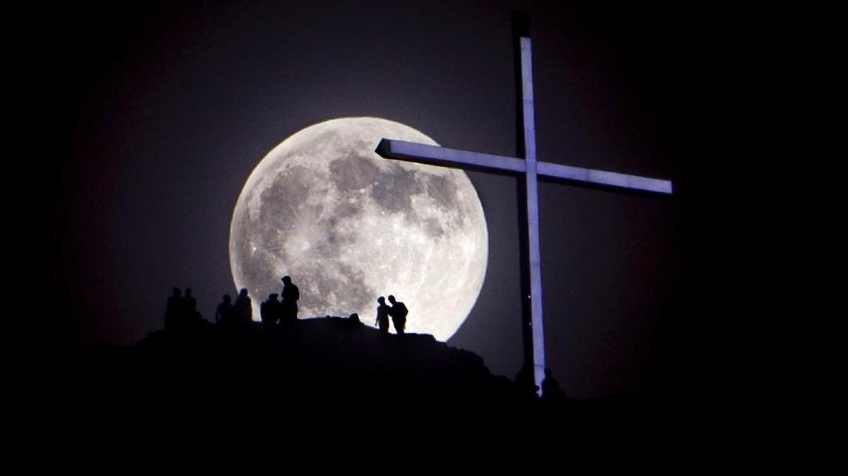 A "supermoon" rises over Table Rock and lighted cross near Boise, Idaho. Saturday June 22, 2013