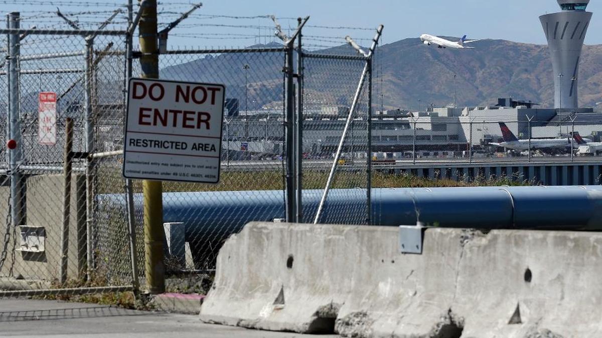 This view from behind fencing at the Millbrae Gate shows a plane taking off from San Francisco International Airport.