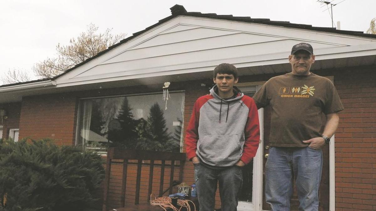 Bob (right) and Brian Packard pose for a photo in front of their home in rural Rigby on Friday afternoon. Brian, 17, was awakened by sharp banging sound Thursday. It turned out there was an intruder in the house.