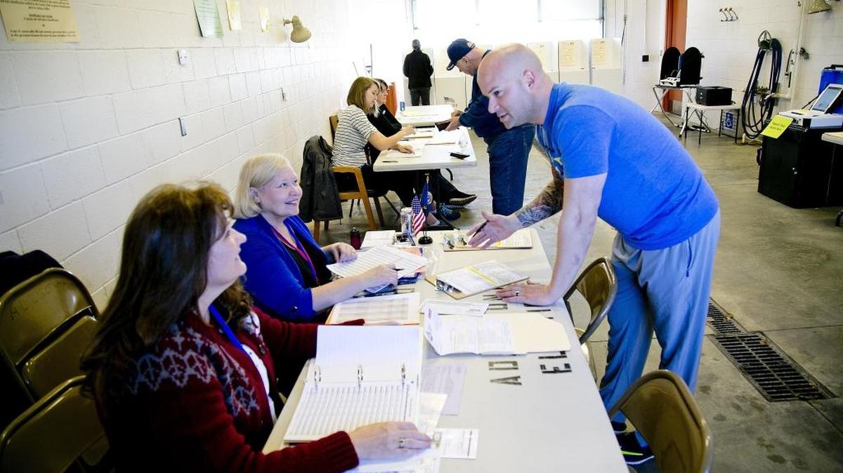 Voter James Moser (right) talks with poll workers Debbie Jackman (left, bottom) and Sandy Thomsen (left, middle) before casting his ballot in the March 8 Republican presidential primary at Precinct 1401 in Star.