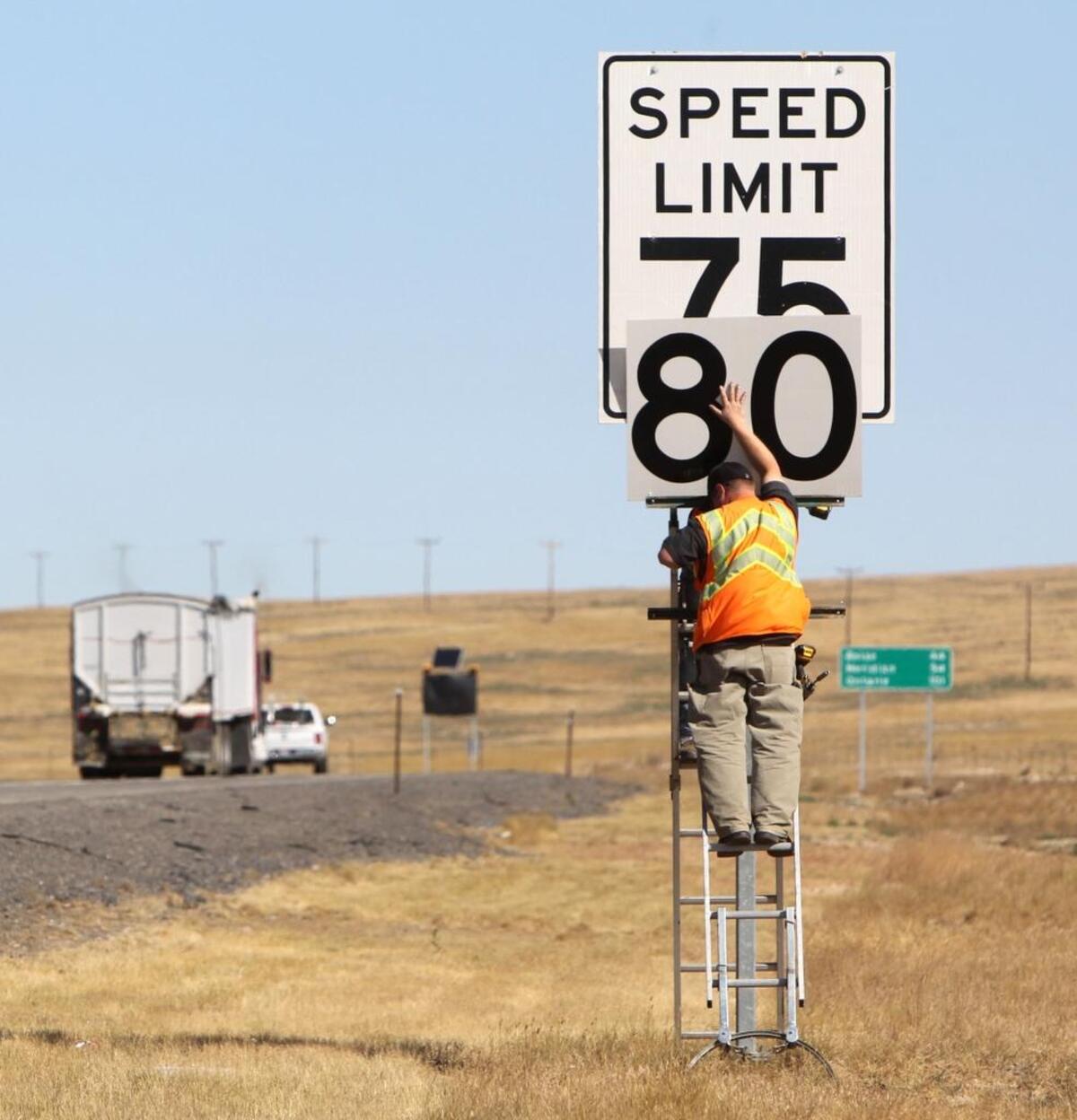 Workers affix new speed limit signs along the westbound lanes of Interstate 84, east of Mountain Home, in July 2014.