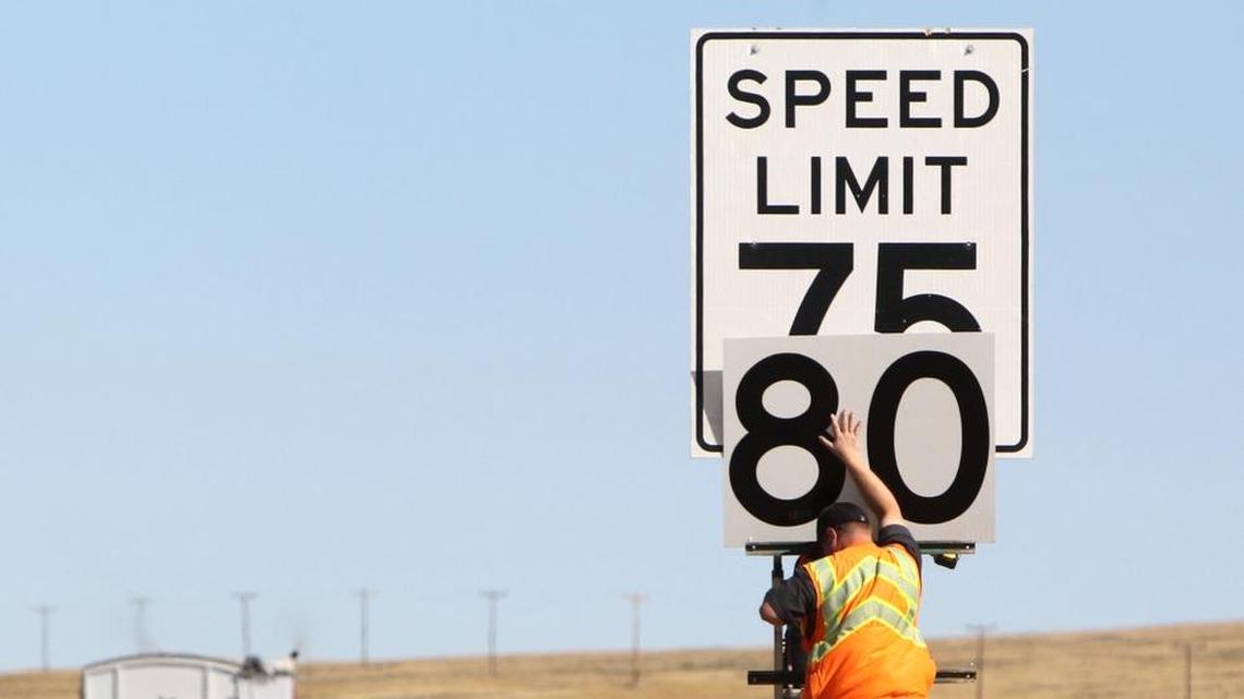Workers affix new speed limit signs along the westbound lanes of Interstate 84, east of Mountain Home, in July 2014.