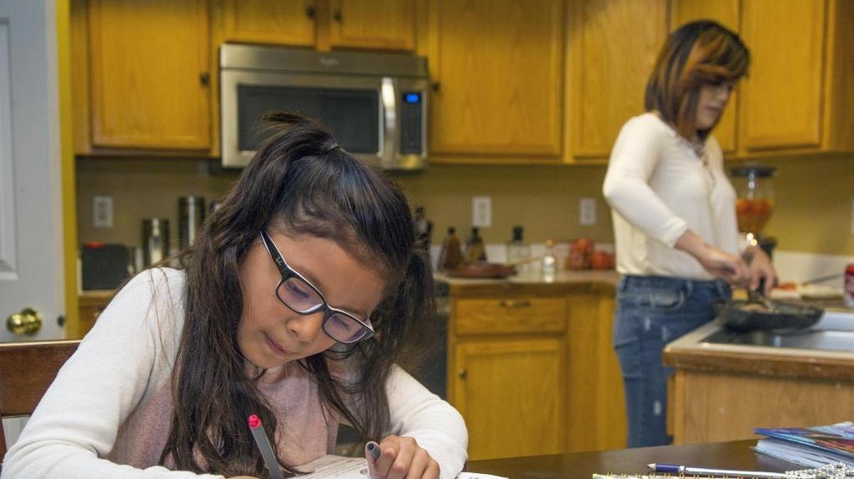 Mia Centeno, 8, colors and signs Christmas gift tags on the dining table while her mother, Nayeli Macias, prepares dinner in their Nampa home. Mia has a rare disorder — one extra bone in her foot — and CHIP (the Children’s Health Insurance Program) helps make her medical care affordable.
