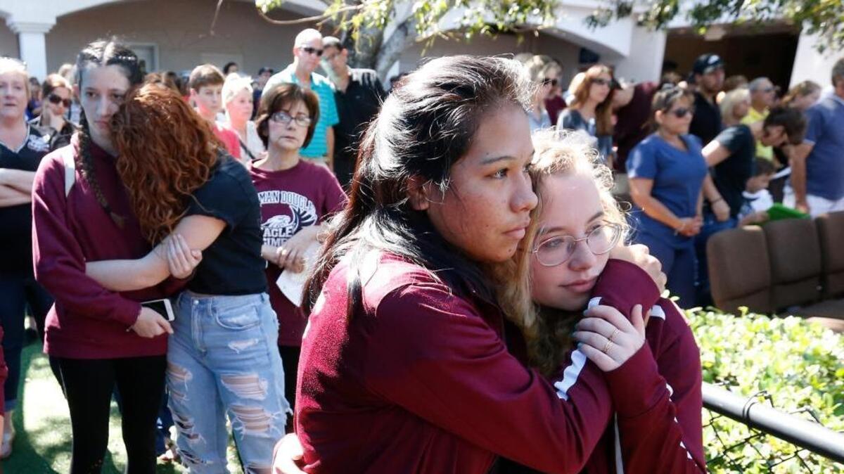 Attendees comfort each other Thursday at a vigil for the victims of the Wednesday shooting at Marjory Stoneman Douglas High School in Parkland, Fla. An orphaned 19-year-old with a troubled past and his own AR-15 rifle was charged with 17 counts of premeditated murder Thursday morning after being questioned for hours by state and federal authorities following the deadliest school shooting in the U.S. in five years.