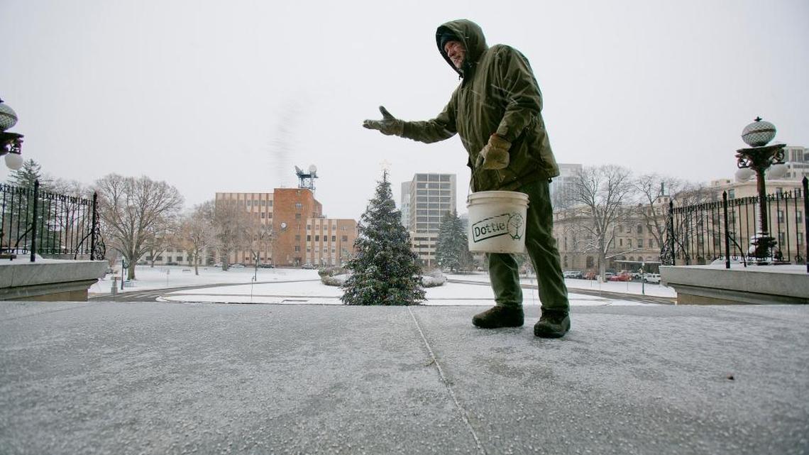 State employee Dan Woodworth spreads Cryotech deicing pellets onto the steps of the Idaho Capitol Thursday.