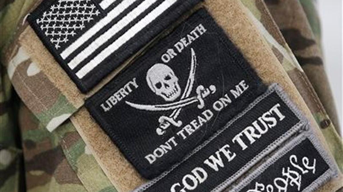 A member of the group occupying the Malheur National Wildlife Refuge headquarters wears a camouflage jacket with a patch on his shoulder Monday near Burns, Ore.