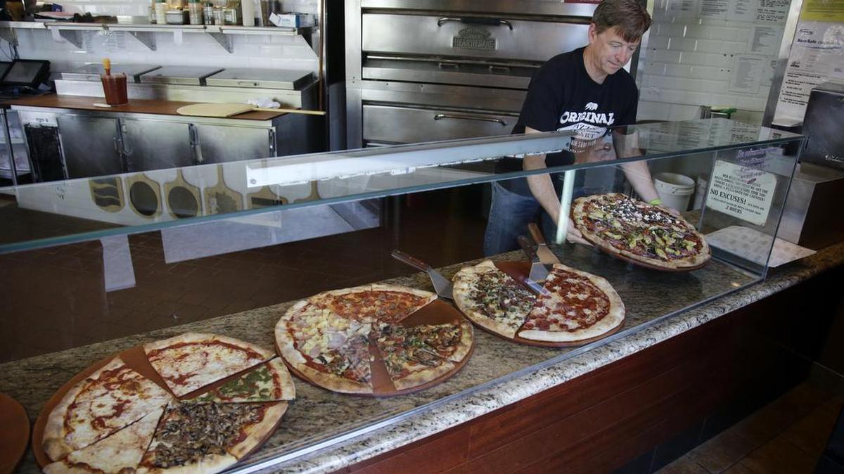 In this March 28, 2016 file photo Chuck Hammers, right, owner of Pizza My Heart, displays one of his pies in San Jose, Calif. California state lawmakers are expected to pass a proposal to gradually raise the minimum wage to a nation-leading $15 an hour by 2022. (AP)