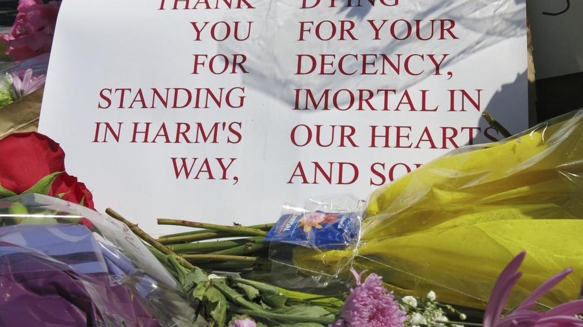 A sign of thanks rests against a traffic light pole at a memorial outside the transit center in Portland, Ore., on Saturday.