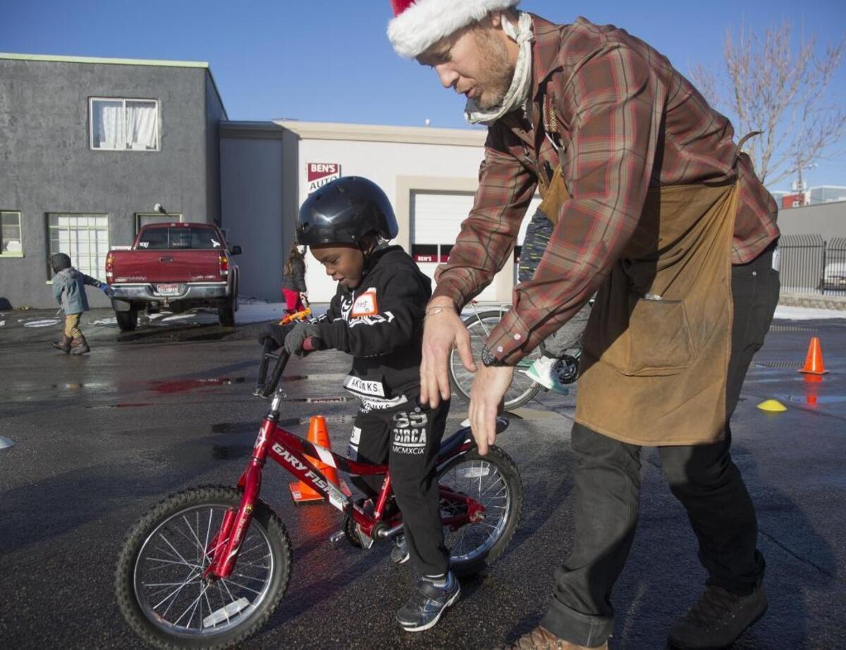 Jimmy Hallyburton, executive director at Boise Bicycle Project, helps 4-year-old Christ Memadji le Allaha learn to ride his first bicycle at the annual Christmas Kids Bike Giveaway Saturday.