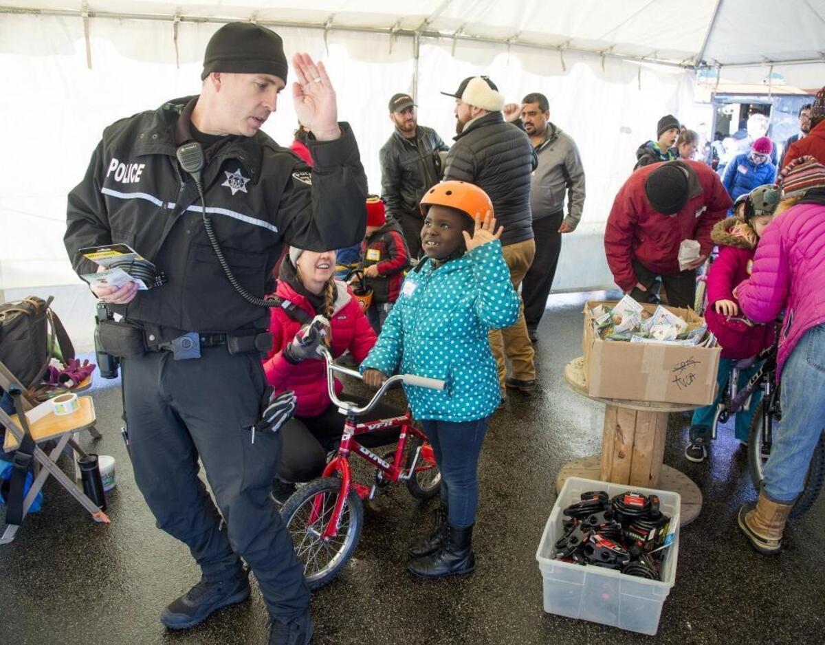 The Treasure Valley Cycling Alliance coordinates safety instruction in a heated tent at the annual bike giveaway. Lynne Memadji le Allaha — who’d just received bicycle, safety helmet, a bike lock and lights — learns how to signal by following Andrew Johnson of the Boise Police bicycle unit. TVCA donated lights for each child, and Primary Health donated helmets.
