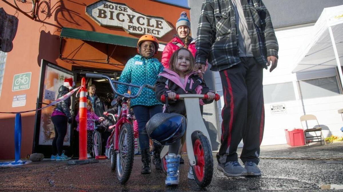 Annie Minshall, 3, rolls out of the Boise Bicycle Project with a big smile and a bicycle just her size Saturday at BBP’s annual Christmas Kids Bike Giveaway. Lynne Memadji le Allaha is in the orange helmet.