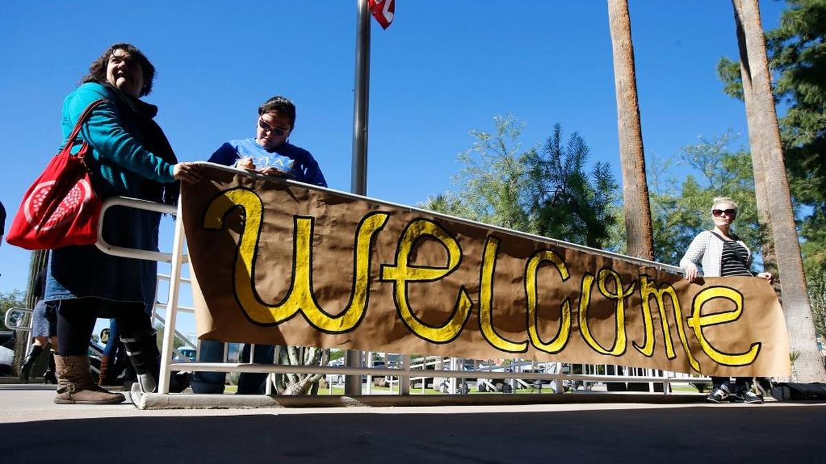 Supporters place a sign welcoming Syrian refugees at the entrance to the office of the Arizona governor during a rally there this week.