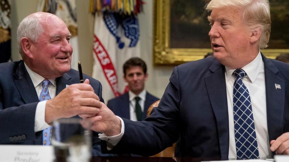 President Donald Trump hands a pen to Agriculture Secretary Sonny Perdue after signing an executive order during farmers' roundtable in the Roosevelt Room of the White House in Washington in April, 2017. (AP)