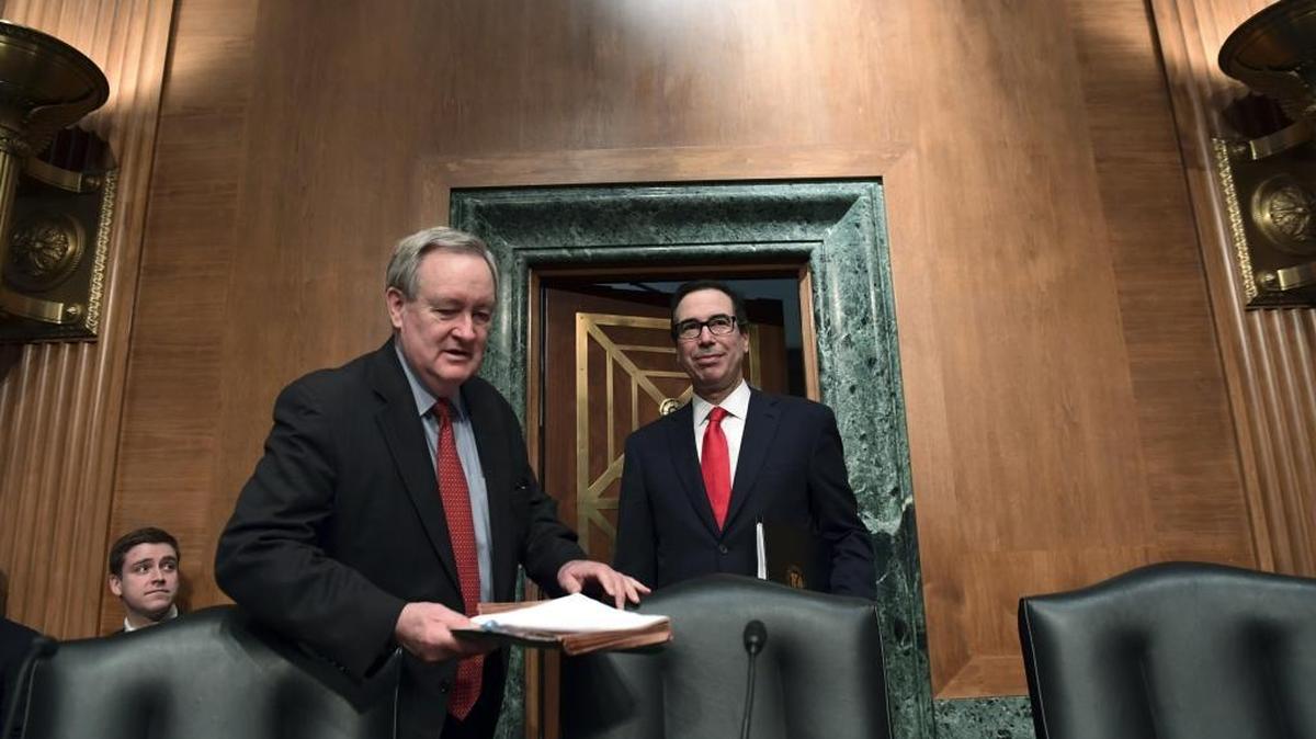 Senate Banking Committee Chairman Mike Crapo, R-Idaho, left, arrives with Treasury Secretary Steven Mnuchin, right, at a Senate Banking Committee meeting in February.