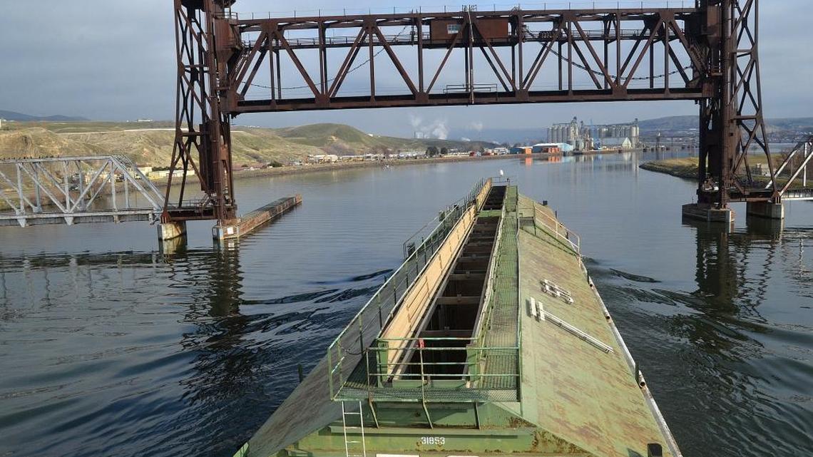 Barge transportation is made possible by the four Lower Snake River dams. Here a tug pushes a barge at the train bridge on the lower Clearwater River.