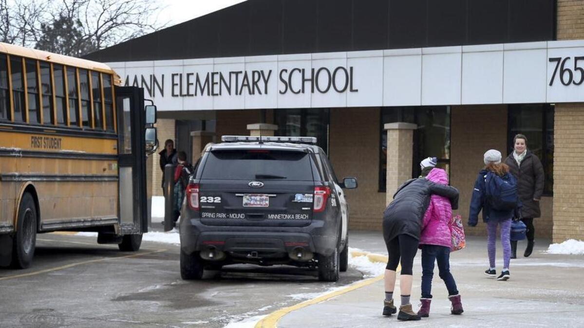 A police officer stands nearby as students arrive at Orono Schumann Elementary School the day after a threat caused Orono, Minn., schools to go on lockdown in February.